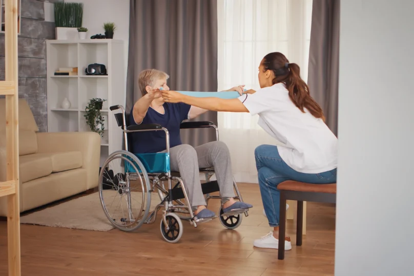senior-woman-wheelchair-doing-rehab-with-resistance-band-training-sport-recovery-lifting-old-person-retirement-home-healthcare-nursing-health-support-social-assistance-doctor-home-s